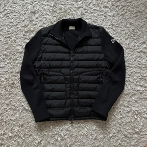 Moncler Cardigan- HELT NY med originella lappar och NFC - Tjena! Säljer en riktigt fet Moncler cardigan i Svart. Den är storlek M och har en perfekt- typisk moncler fit. Den är helt perfekt för våren, hösten men även vintern vilket gör den till ett mångsidigt plagg man kan använda året runt. Den är HELT NY med ALLA ORIGINELLA LAPPARNA KVAR, även påsen den kom med. NFC funkar såklart. Priset kan diskuteras, har ej kvitto och det är anledningen till att jag säljer billigare än nypris även om den är helt ny och aldrig använd.  