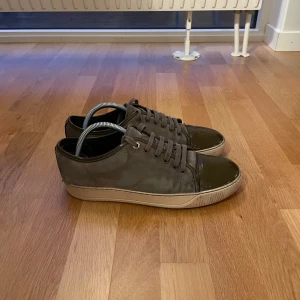 Lanvin Sneakers - Snygga sneakers från Lanvin med snörning och en stilren design. Skorna har en ljus sula och är perfekta för en avslappnad stil. Färgen är olivgrön men ser nästan grå ut. Passform runt 42 Okej skick! Obs! Inget OG tillkommer, därav priset! Hör av dig vid fler frågor eller funderingar! MVH Ludvig