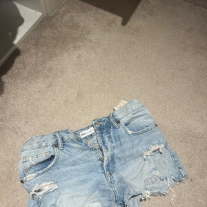 Ljusa jeansshorts från Zara - Snygga ljusa jeansshorts från Zara med slitna detaljer och fransar. Perfekta för en avslappnad stil. De har en klassisk femficksdesign och knappgylf.