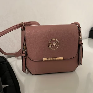 MK väska  - Säljer en mk väska. Den är använd så säljs därför för 50 kr. Den är jättefin inga skador på materialet endast att metallen har blivit lite gammal.