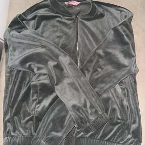 Grå kofta från Hunkemöller - Snygg grå kofta från Hunkemöller i mjukt sammetstyg. Jackan har en dragkedja framtill och långa ärmar med ribbade muddar. Perfekt för en stilren look.