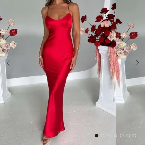 Röd klänning från Babyboo - Röd långklänning i satin med smala axelband och öppen rygg. Klänningen är helt oanvänd och har lappen kvar! Pris kan diskuteras:)