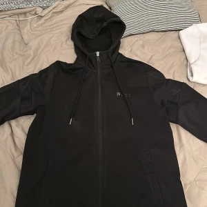 Hugo boss zip hoodie - En Hugo boss zip hoodie ganska använd i storlek m, en bokstav på loggan är av annars är den bra och skön att ha på sig