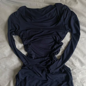 Mörkblå klänning - Snygg mörkblå klänning med långärmad design och rynkade detaljer på sidan. Passar mig som är 170 och passar även XS, S, M, L då den är stretch (brukar ha liten S)