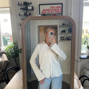 Vit långärmad skjorta - Säljer en stilren vit skjorta med långa ärmar. Skjortan har en klassisk krage och knappar framtill.