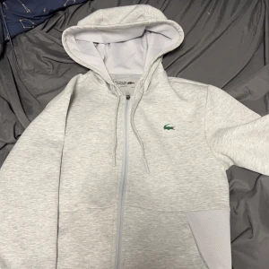 Lacoste zip hoodie - Grå lacoste hoodie  Skick 9/10 värd 1000 nypris mitt pris 600 priset kan diskuteras 