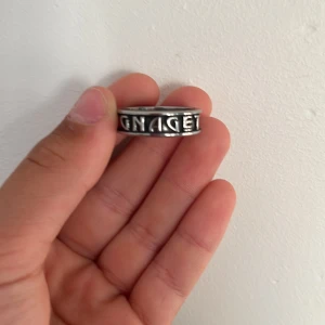 Silverfärgad ring med silver AIK/GNAGET bokstäver ⬛️🟨⬛️ - Säljer en cool silverfärgad ring med upphöjd text runtom. Den har en stilren och modern design som passar perfekt till både vardag och fest. Ringen är i bra skick och redo att bäras av någon som vill ha en unik accessoar.