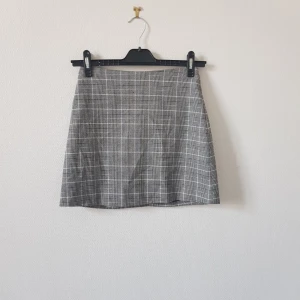 Rutig kjol från Monki - Tutig kjol från Monki i storlek 34. Den har ett klassiskt rutmönster i svart och vitt. Kjolen är kort och har en dragkedja.