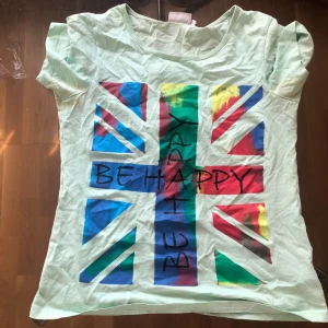 En multifärgade tröja - En multifärgad tröja med regnbågsfärger en texter med titeln Be happy