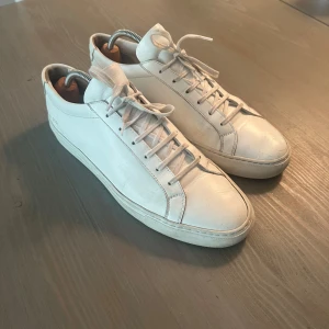 Common Projects  - Common Projects Achilles low white Ett par riktigt schyssta, högkvalitativa skor i ett väldigt fint skick. Ett litet märke på ena skon.  Nypris runt 3900kr Tyvärr ingen box eller kvitto