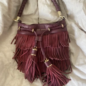 Vinröd Ted baker väska  - Helt perfekt skinn väska från Ted baker! Helt ny!! Unik med fransar