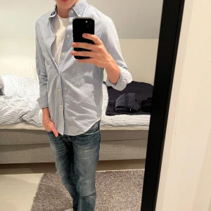 Ljusblå skjorta från Ralph Lauren - Säljer en stilren ljusblå skjorta från Ralph Lauren med broderad logotyp på bröstet. Skjortan har en klassisk design med knappar och långärmade ärmar. Perfekt för en avslappnad men ändå uppklädd look. DEN SITTER SOM XS! Jag e 175!