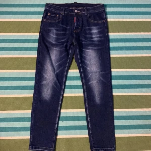 Mörkblå jeans med slitningar - Snygga mörkblå jeans med diskreta slitningar och klassisk femficksdesign. De har en knappgylf och är perfekta för en avslappnad stil. Passar bra till både t-shirt och skjorta.