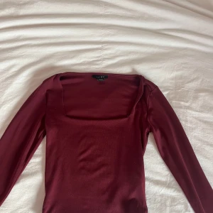 Vinröd topp från Amisu - Snygg vinröd topp från Amisu med långärmad design och fyrkantig halsringning.  Tillverkad i ett mjukt och bekvämt material.