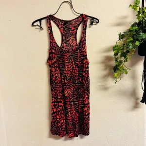 Sexig miniklänning med möster i rosa, orange och svart - Snygg miniklänning med djärvt mönster i rosa, orange och svart. Storlek Small. Skön stretchig viskos. Den har en ärmlös design med brottarrygg. Från Gina Tricot. Mycket bra skick. Perfekt för att sticka ut i mängden!