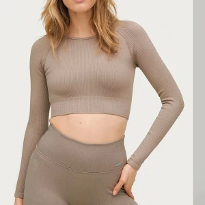 Beige ribbad croppad topp Aimn - Säljer en beige ribbad croppad topp från Aimn. Toppen har långa ärmar och en stilren design som passar perfekt för en trendig look och till träning. Perfekt för dig som vill ha något bekvämt och snyggt samtidigt. Mycket bra skick!!