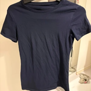 Mörkblå t-shirt från Intimissimi - Säljer en stilren mörkblå t-shirt från Intimissimi i Supima bomull. Den har en klassisk rund hals och korta ärmar, perfekt för en enkel och bekväm look. Passar bra till både jeans och kjol. Perfekt basplagg för garderoben!