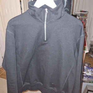 Svart tröja med dragkedja från Zara - Säljer en stilren svart tröja från Zara med halv dragkedja och hög krage. Perfekt för kyligare dagar och enkel att matcha med olika outfits. Tröjan har långa ärmar och är tillverkad i ett mjukt material.