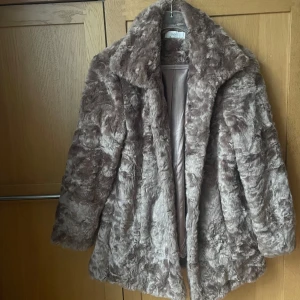 Brun faux pälsjacka från lyxigt märke Wallis London - Säljer en lyxig brun pälsjacka från Wallis london. Jackan har en klassisk krage och är perfekt för kyligare dagar. Den är långärmad och har en mjuk och fluffig yta som ger en lyxig känsla. Nypris 1000 kr. 