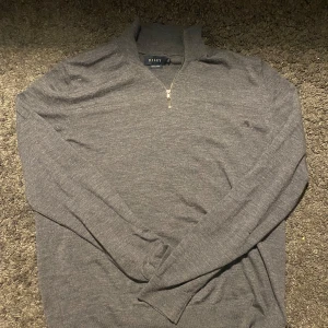 Grå tröja med dragkedja från Billey - Säljer en stilren grå tröja från riley med dragkedja vid halsen. Tröjan har långa ärmar och är perfekt för en avslappnad look. Passar bra till både jeans och chinos.