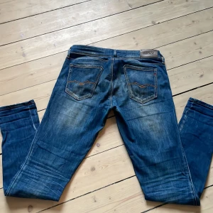 Blå jeans från Replay - Snygga blå jeans från Replay med klassisk femficksdesign och snygga detaljer. De har en normal passform och är perfekta för en avslappnad stil. Märkeslogga på baksidan och vid fickan ger en extra touch.