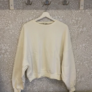 Vit sweatshirt - Säljer en vit sweatshirt från Nly med ribbade muddar vid ärmslut och hals. Tröjan är oversized i passform och som ny. Har mest legat i en låda.