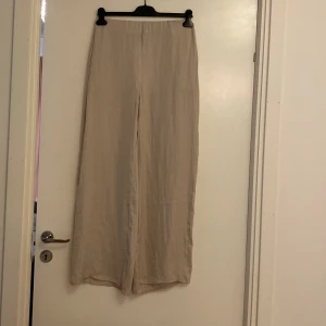 Beige byxor från Gina Tricot - Säljer ett par snygga och bekväma beige byxor från Gina Tricot. De är i storlek 36 och har en loose passform med hög midja. Perfekta för en avslappnad stil eller en dag på stan. Materialet känns mjukt och luftigt, vilket gör dem idealiska för vår och sommar.