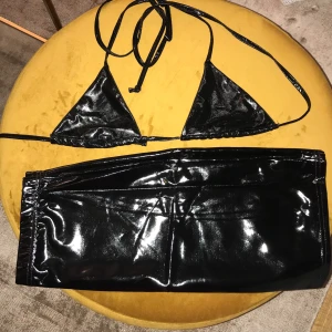 Lack-set, topp och kjol - Topp och kjol i svart lack, nyskick. Dominatrix-vibes 🖤 Top 38 men one-size, passar alla, kjolen likaså (storlek 38)