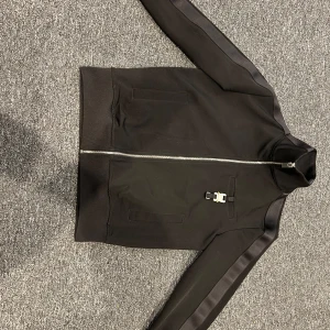 1017 ALYX Buckle Top - Säljer denna alyx zipen. Den har ALDRIG använts. Passar inte bra på mig så har endast legat i garderoben. Kvitto ska finnas någonstans på mailen.  Fraktas / hämtas i Karlskrona