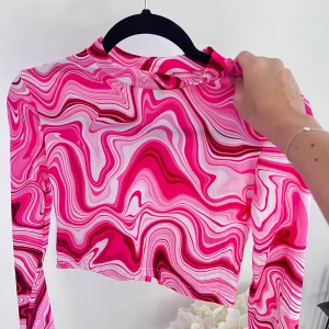 Croppad rosa långärmad teöja - En långärmad croppad tröja i härligt rosa mönster 💞 Säljer pga att den aldrig kom till användning! Tröjan har en 2-3 cm krage och är i skönt material. Passar bra till mig som normalt har storlek S i toppar 😚  (ALDRIG ANVÄND)  Längd: 39 cm Byst: 84 cm