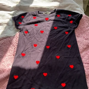 Svart klänning med röda hjärtan - Säljer en superfin svart klänning med röda hjärtan. Den är kortärmad och har en normal passform. Perfekt för en söt och lekfull look! 🖤❤️