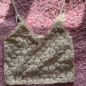 Beige spetslinne - Säljer ett superfint beige spetslinne med blommigt mönster. Det är croppat och har smala axelband, perfekt för sommaren eller en fest. Linnet är i nyskick och ger en romantisk och bohemisk känsla.