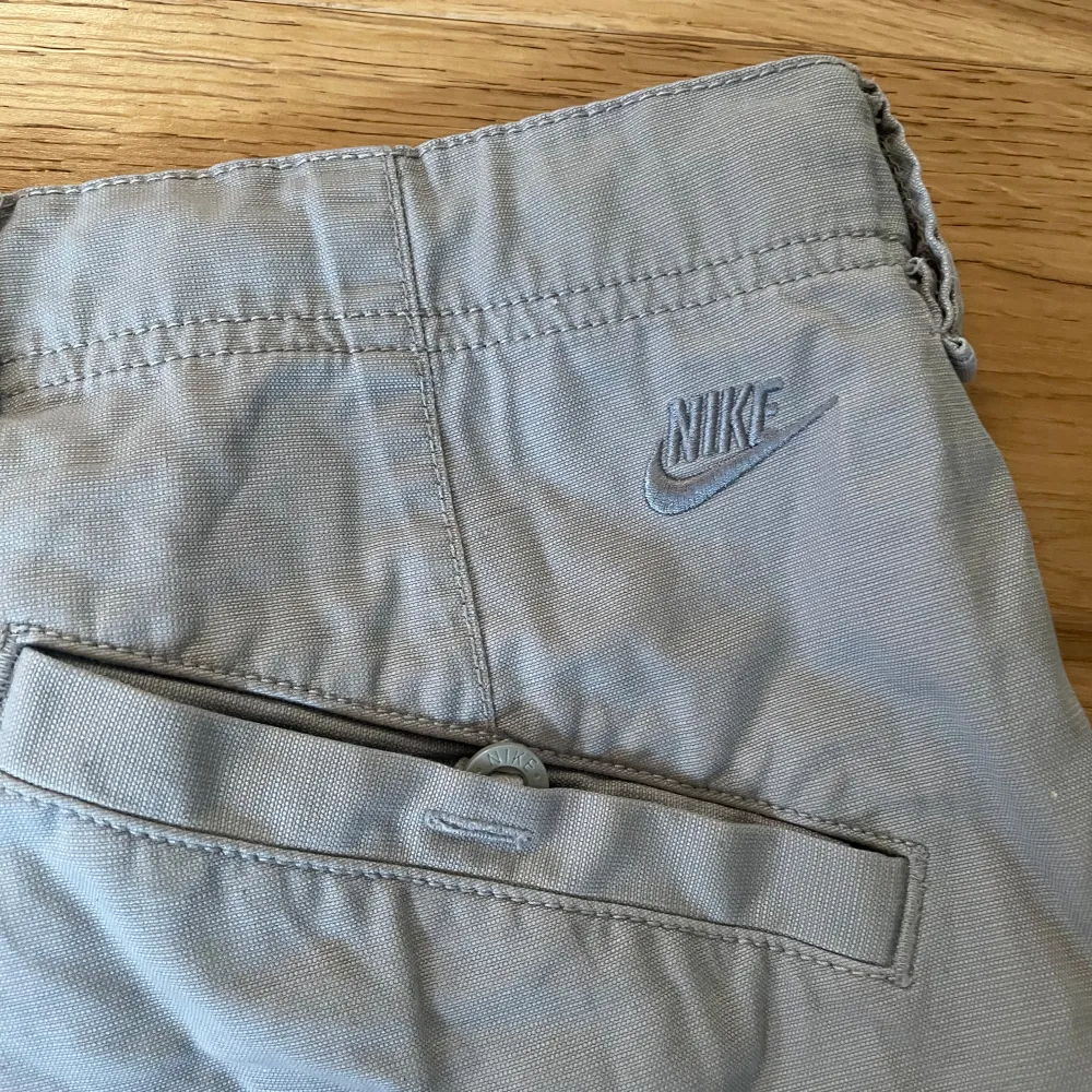 Ett par beige/grå cargo pants från Nike. Baggy fit med snören så man kan dra åt vid fötterna. Köpt secondhand, men endast använda få gånger.   Skriv för fler bilder eller mått!!. Jeans & Byxor.