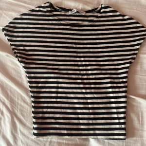 Randig topp från Zara - Säljer en snygg randig topp från Zara i svart och vit. Den har korta ärmar och en normal passform, perfekt för en avslappnad stil. Toppen är i bra skick och passar till både vardag och fest!