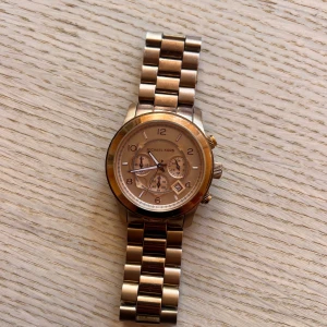 Michael Kors klocka  - Säljer en damklocka från Michael Kors i roséguld (MK8096). Funkar fint MEN behöver byta batteri då jag inte använt den på länge…  Diameter: Ø 45.00 mm Boett: Roséguldstonat stål Urtavla: Roséguldstonad med självlysande siffror och visare