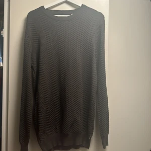 Olivgrön tröja från Kronstadt - Säljer en olivgrön tröja från Kronstadt med ett subtilt mönster. Tröjan har långa ärmar och rund halsringning, perfekt för en stilren look. Passar bra till både jeans och chinos. Sitter som L
