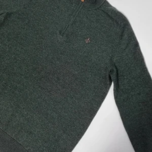 Grön ulltröja från Morris - Säljer en stilren grön ulltröja från Morris med dragkedja och liten broderad logga på bröstet. Perfekt för kyligare dagar med sin mjuka och varma känsla. Tröjan har långa ärmar och en klassisk passform.