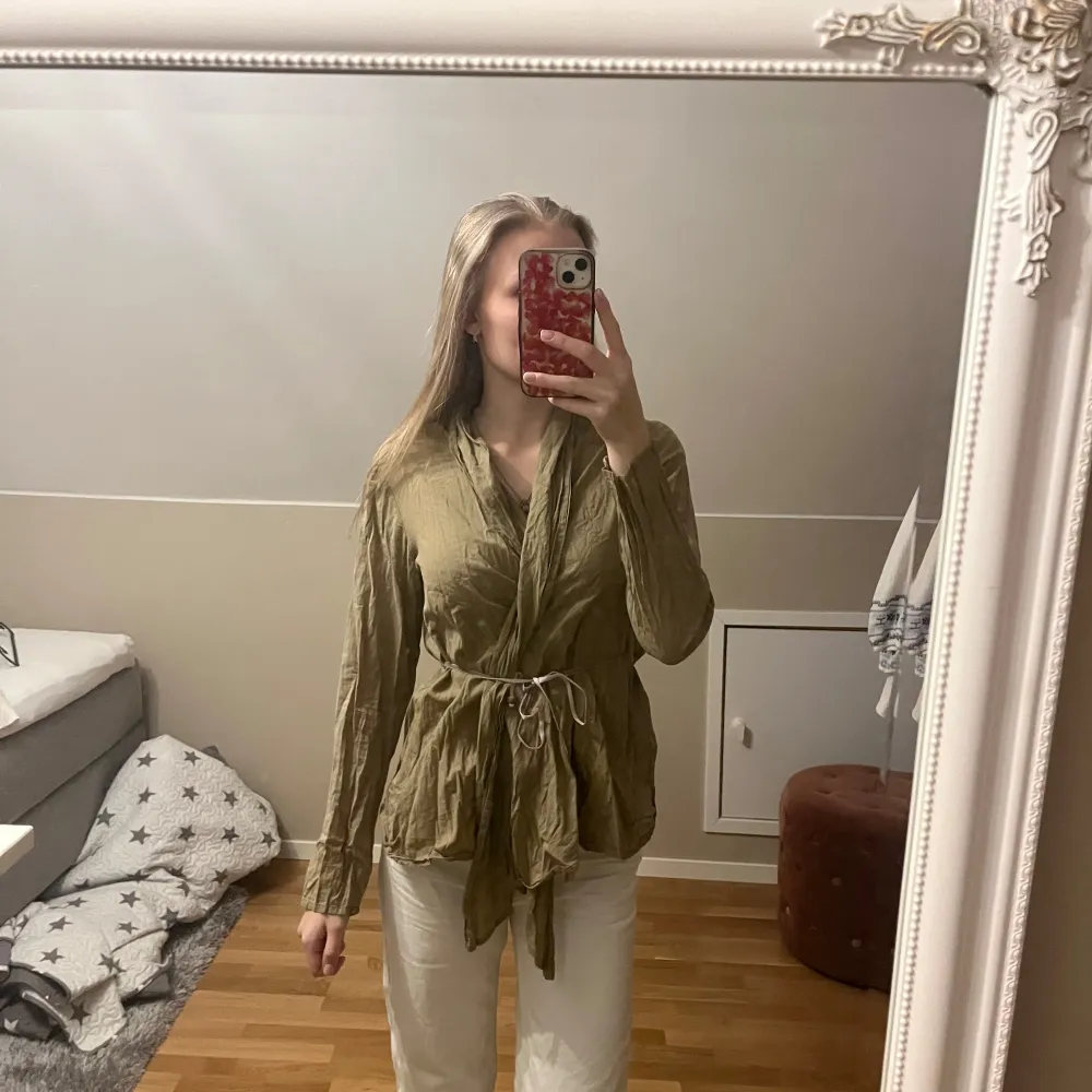 Säljer en olivgrön/brun blus från Vintage by Fé med vackra spetsdetaljer på ryggen💕 Jackan har långa ärmar och ett knytband i midjan för en justerbar passform😁Perfekt för en bohemisk stil🌿Blusen är väldigt luftig och skön på sommaren☀️ Passar allt från XS till M😇. Puserot.