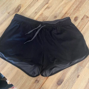 Svarta sportshorts från H&M -  svarta sportshorts från H&M med elastisk midja. Perfekta för träning eller en avslappnad dag. Materialet är lätt och andas, vilket gör dem bekväma att bära under intensiva aktiviteter.