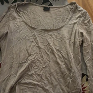 Beige långärmad topp från Gina Tricot - Säljer en beige långärmad topp från Gina Tricot. Toppen har en rund halsringning och är tillverkad i ett mjukt material som känns skönt mot huden. Perfekt för en avslappnad stil.