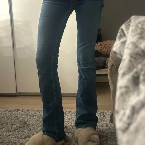Blå bootcut jeans från Zara - Snygga blå bootcut jeans från Zara med klassisk femficksdesign. De har en hög midja och en bekväm passform som sitter snyggt över höfterna och låren innan de går ut i en bootcut-stil. Perfekta för en avslappnad look.
