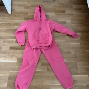 Rosa hoodie och byxor från Barbara Kristoffersen - Säljer en rosa hoodie och matchande byxor från Barbara Kristoffersen. Hoodien har en stor ficka framtill och en justerbar huva. Perfekt för en avslappnad stil. Det finns en liten fläck på tröjan. 100kr styck eller 180kr för båda, bästa mjukissetet som finns, passformen är guld, har i flera färger använder bara inte det här längre.