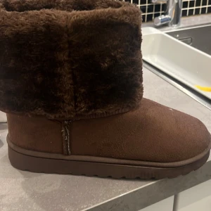 Bruna boots med pälsdetalj - Säljer ett par bruna boots med mjuk pälsdetalj runt skaftet. Perfekta för att hålla fötterna varma under kyliga dagar. Storlek 41