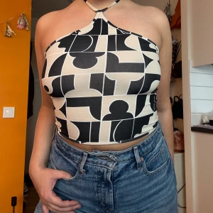 Mönstrad halterneck topp  - Säljer en cool halterneck topp från Monki med ett svart och beige geometriskt mönster.  Oanvänd bara provad så mkt bra skick. 