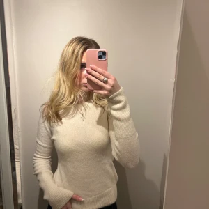 Vit stickad  - Säljer en stilren vit stickad tröja med långa ärmar. Tröjan har en klassisk design med ribbade muddar vid ärmslut och hals. Perfekt för kyligare dagar. Tröjan är insydd och har även en fläck på mudden som man ser på bild 3 och missfärgad vid missen( bild 2)💓💓