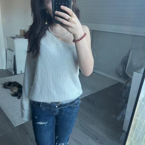 Vit offshoulder tröja - Säljer en stilren vit offshoulder tröja med en avslappnad passform. Tröjan är stickad och har långa ärmar, perfekt för en casual look. Passar bra till jeans eller kjol för en trendig outfit.