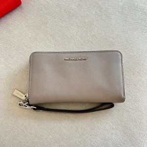 Michael Kors plånbok - Grå plånbok med band från Michael Kors