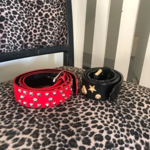 rött/rosa nitskärp och svart skärp! - två skit coola skärp! det svarta är slitet (tredje bilden) och har tappat diamanter på detaljerna (två sista bilderna) och det rosa nitskärpet är i nyskick! längden på svarta är 87cm till sista hål och det röd/rosa är 97cm