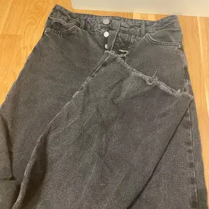 Säljer ett par svarta jeans med en cool, rå kant vid bensluten. De har en klassisk femficksdesign och knappar i midjan. Perfekta för en avslappnad och trendig look!