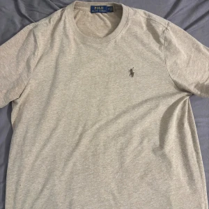 T-shirt från Polo Ralph Lauren - Säljer en stilren kaki t-shirt från Polo Ralph Lauren. Den är kortärmad och har en broderad logga på bröstet. Perfekt för en avslappnad stil, gjord i mjuk bomull för extra komfort. Varan är testat 1 gång och var en present som inte passa min stil.